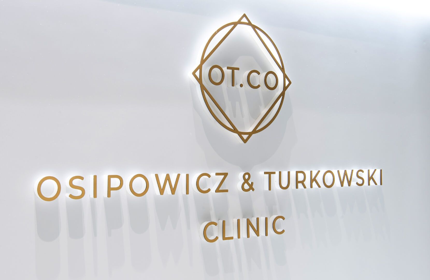 Lettere spaziali nell'area di accoglienza della clinica OT.CO - Lettere spaziali dorate con logo nell'area della reception della clinica OT.CO
